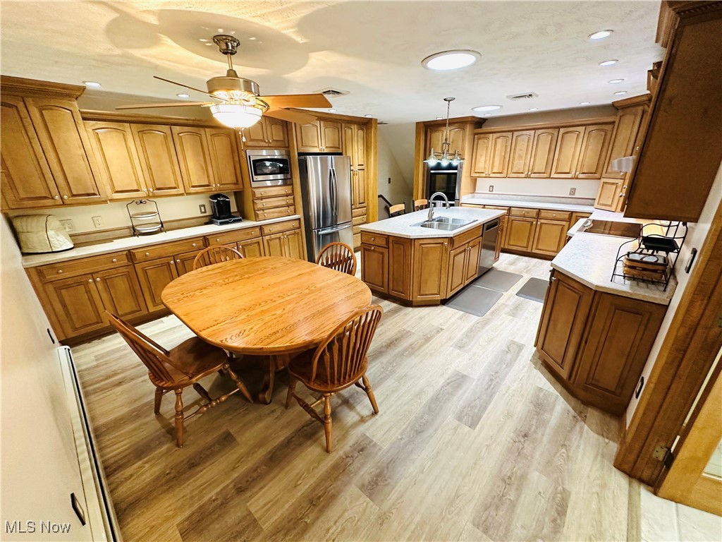 1684 Morris Street Mineral Ridge, OH 44440 - Photo 4 of 50 Kitchen featuring stainless steel appliances, a sink, an island with sink, brown cabinets, and light countertops