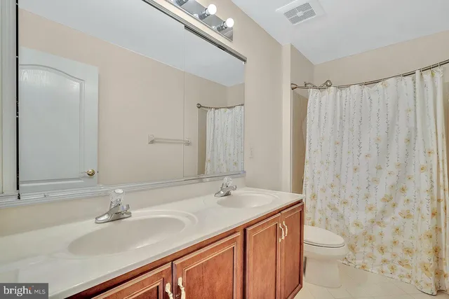 a bathroom with a sink a toilet a mirror and shower curtain