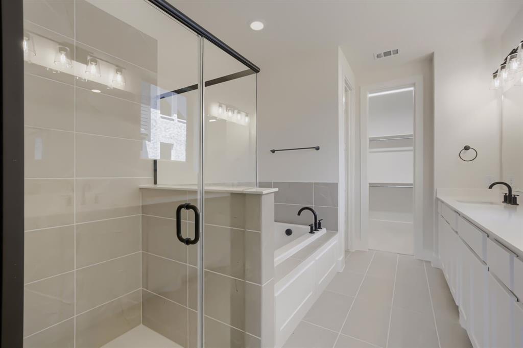824 Stone Grv Road Lavon, TX 75166 - Photo 20 of 26 Contemporary bathroom featuring a glass-enclosed shower, built-in soaking tub, dual vanity with undermount sinks, and matte black fixtures
