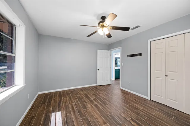 a view of empty room with wooden floor and fan