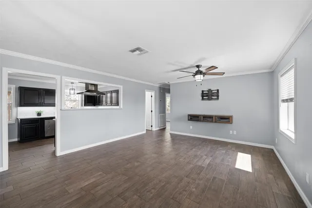 a view of an empty room with a window and wooden floor