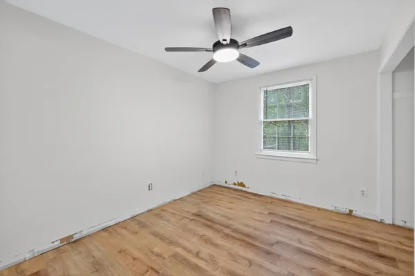 a view of an empty room with wooden floor and a window