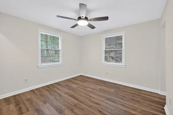 a view of an empty room with wooden floor and a window