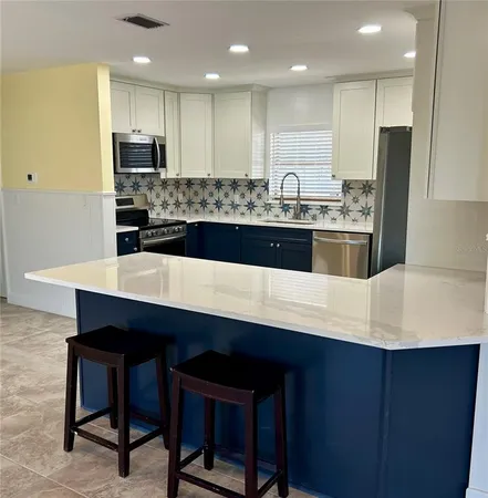 a kitchen with stainless steel appliances a sink a stove a refrigerator with white cabinets and wooden floor