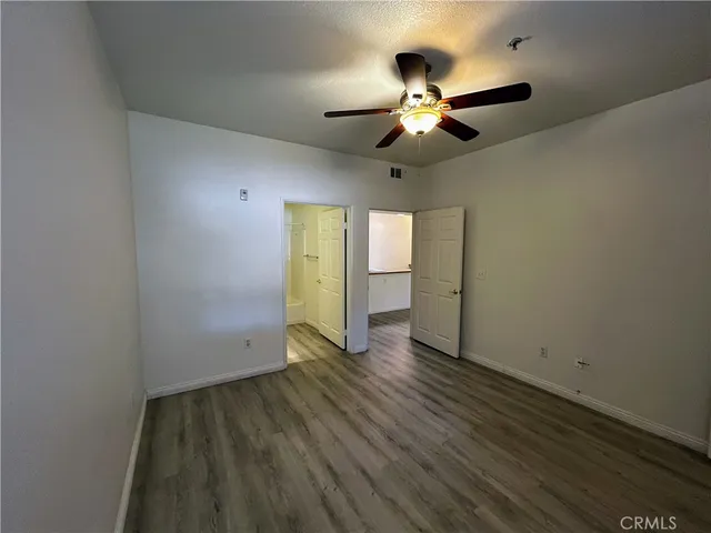 an empty room with wooden floor chandelier fan and windows