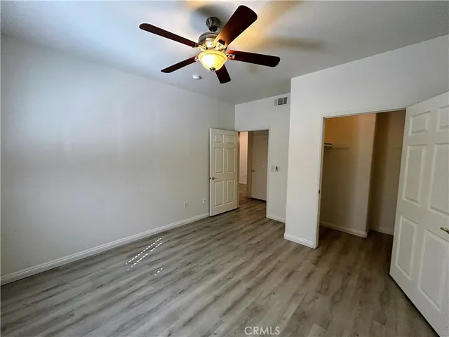 an empty room with wooden floor and a ceiling fan