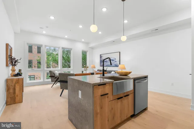a living room with stainless steel appliances granite countertop couches a table and chairs in it
