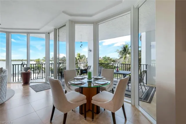 a dining room with furniture water view and a floor to ceiling window