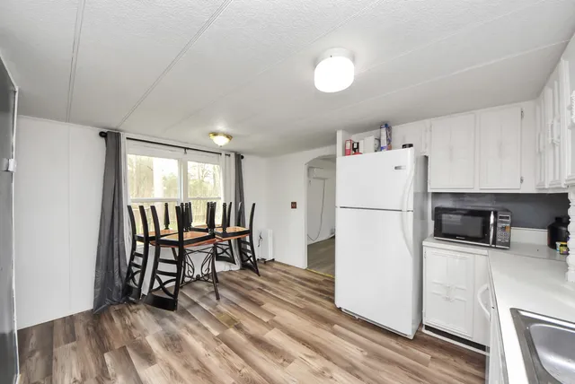 a kitchen with stainless steel appliances a refrigerator a stove a dining table and chairs with wooden floor