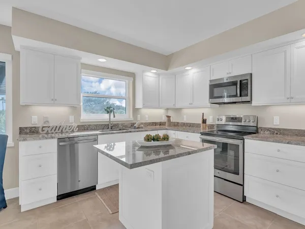 a kitchen with granite countertop white cabinets sink and stainless steel appliances