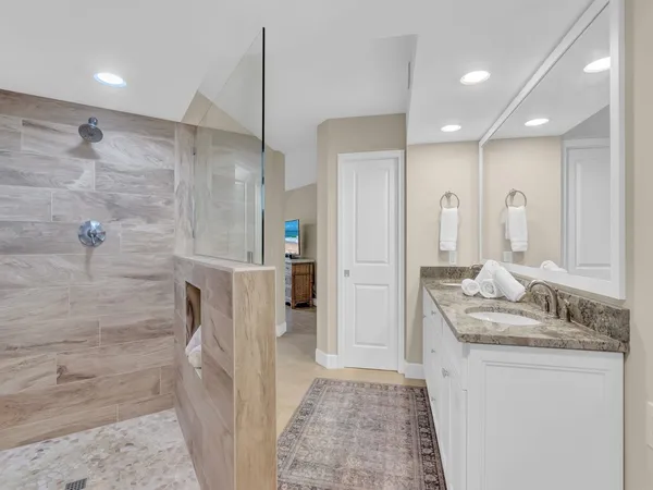 a bathroom with a granite countertop sink a mirror and shower