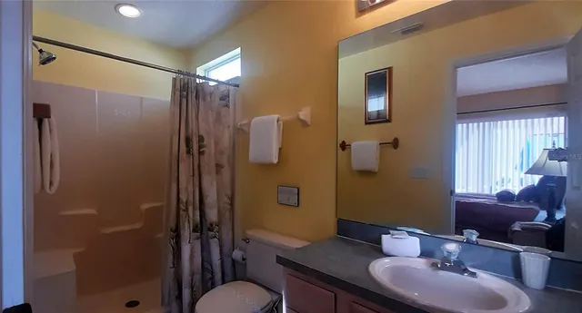 a bathroom with a granite countertop sink toilet a mirror and shower
