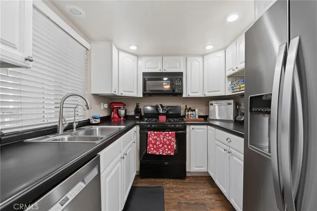 a kitchen with stainless steel appliances granite countertop a refrigerator a sink a stove and cabinets