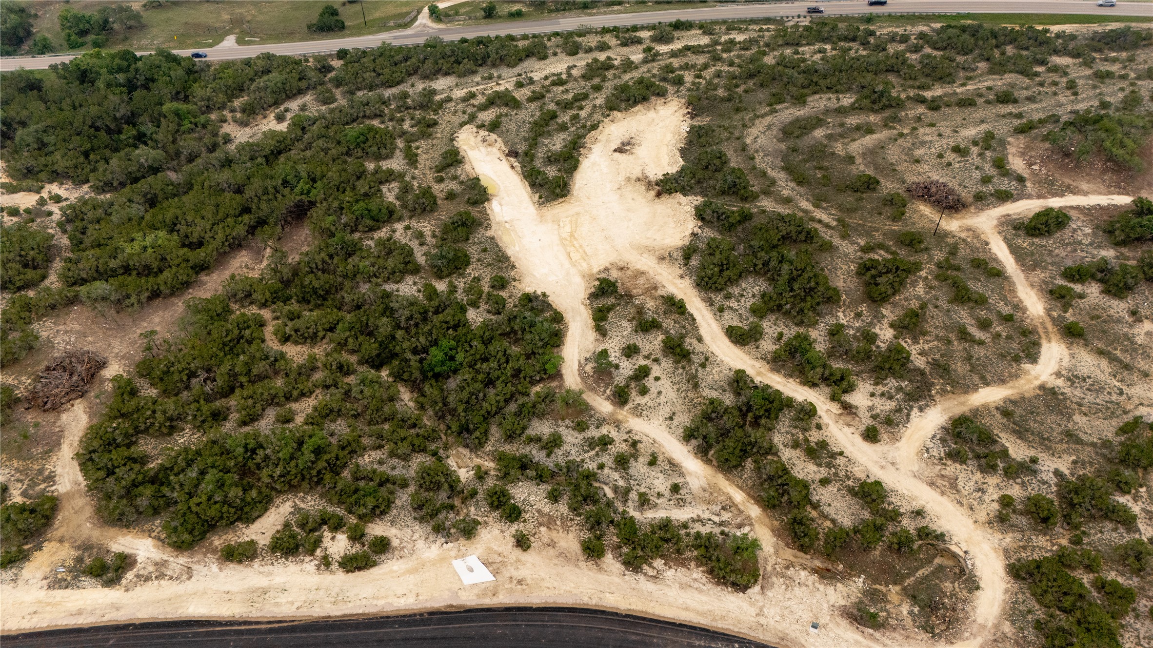 Lot 3 Ranch Road 165 Dripping Springs, TX 78620 - Photo 2 of 11 Expansive undeveloped land featuring natural foliage and a cleared path, bordered by a paved road