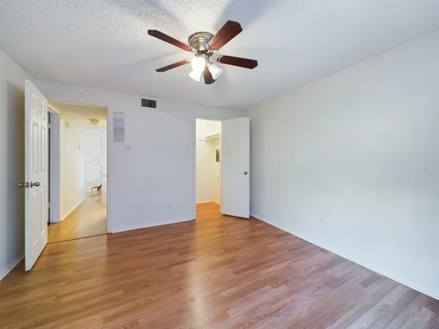 an empty room with wooden floor and a ceiling fan