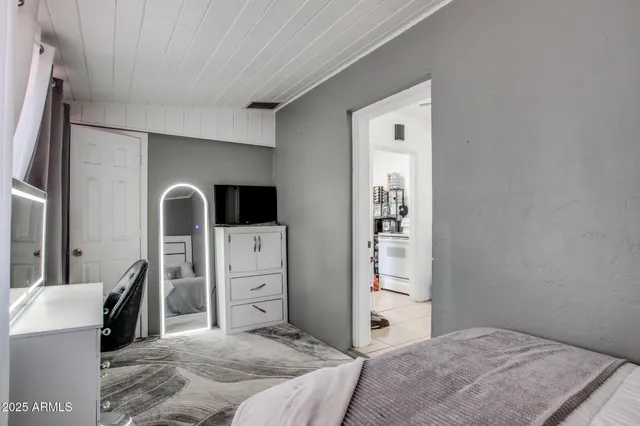 a bedroom with a bed and a large mirror on the dresser