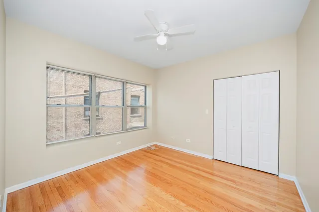 a view of empty room with wooden floor and fan