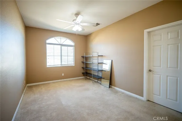 an empty room with chandelier fan and windows