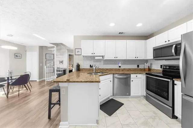 a kitchen with stainless steel appliances granite countertop a stove top oven a sink a dining table and chairs