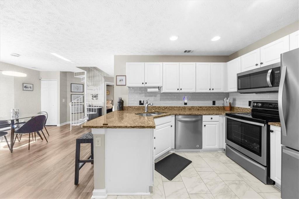 820 Camelon Court Alpharetta, GA 30004 - Photo 13 of 33 a kitchen with stainless steel appliances granite countertop a stove top oven a sink a dining table and chairs