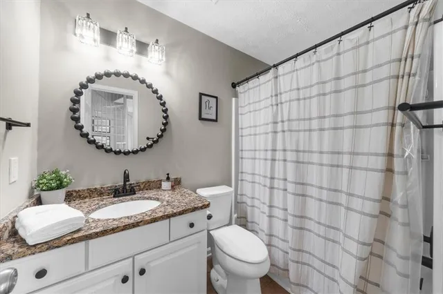 a bathroom with a granite countertop sink mirror vanity and toilet