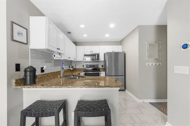 a kitchen with stainless steel appliances granite countertop a sink refrigerator and cabinets