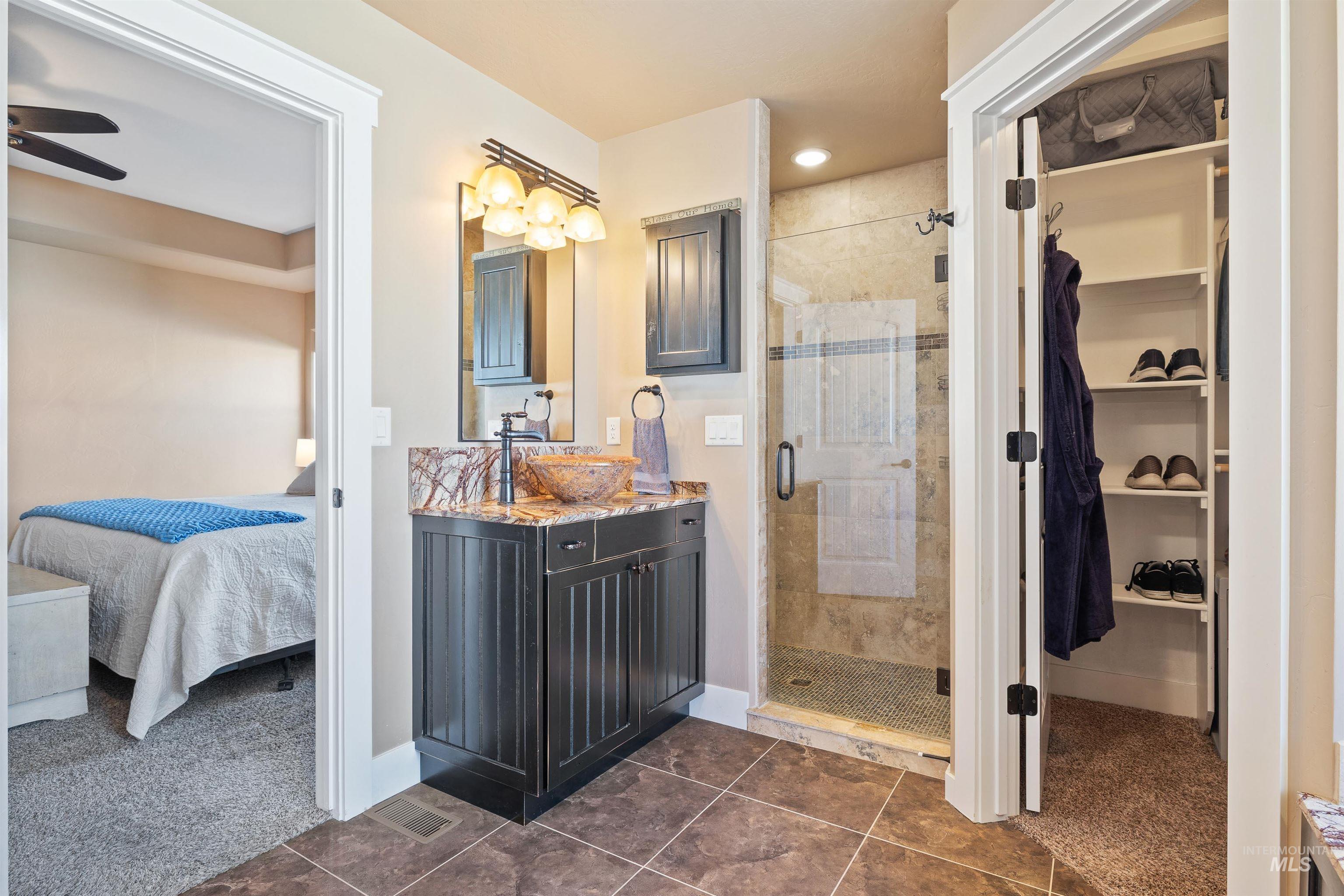 330 Arrowhead Path Twin Falls, ID 83301 - Photo 13 of 37 Ensuite bathroom featuring vanity, a stall shower, dark colored carpet, a walk in closet, and dark tile patterned flooring
