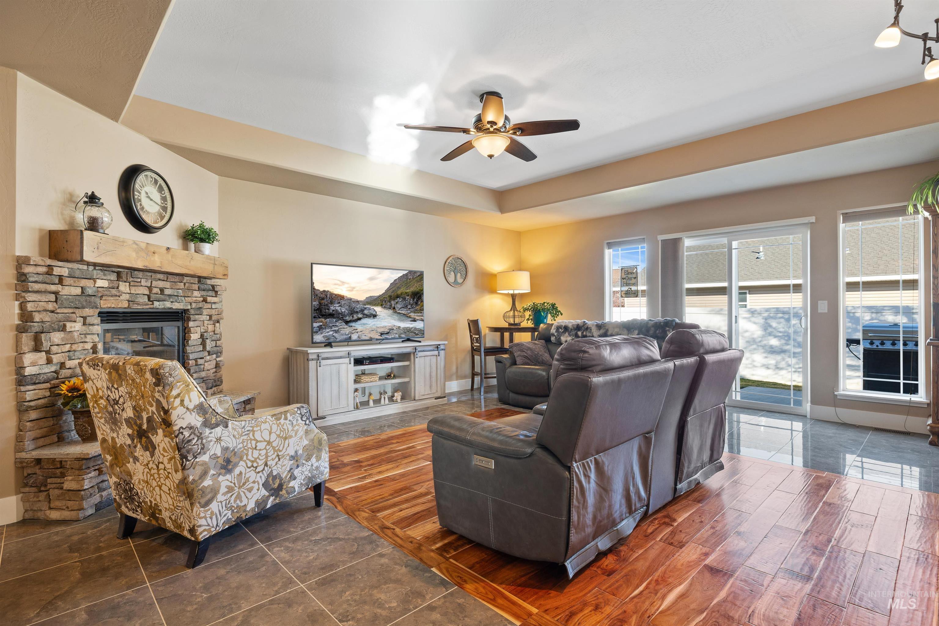 330 Arrowhead Path Twin Falls, ID 83301 - Photo 4 of 37 Living room featuring a stone fireplace, ceiling fan, wood finished floors, and a tray ceiling