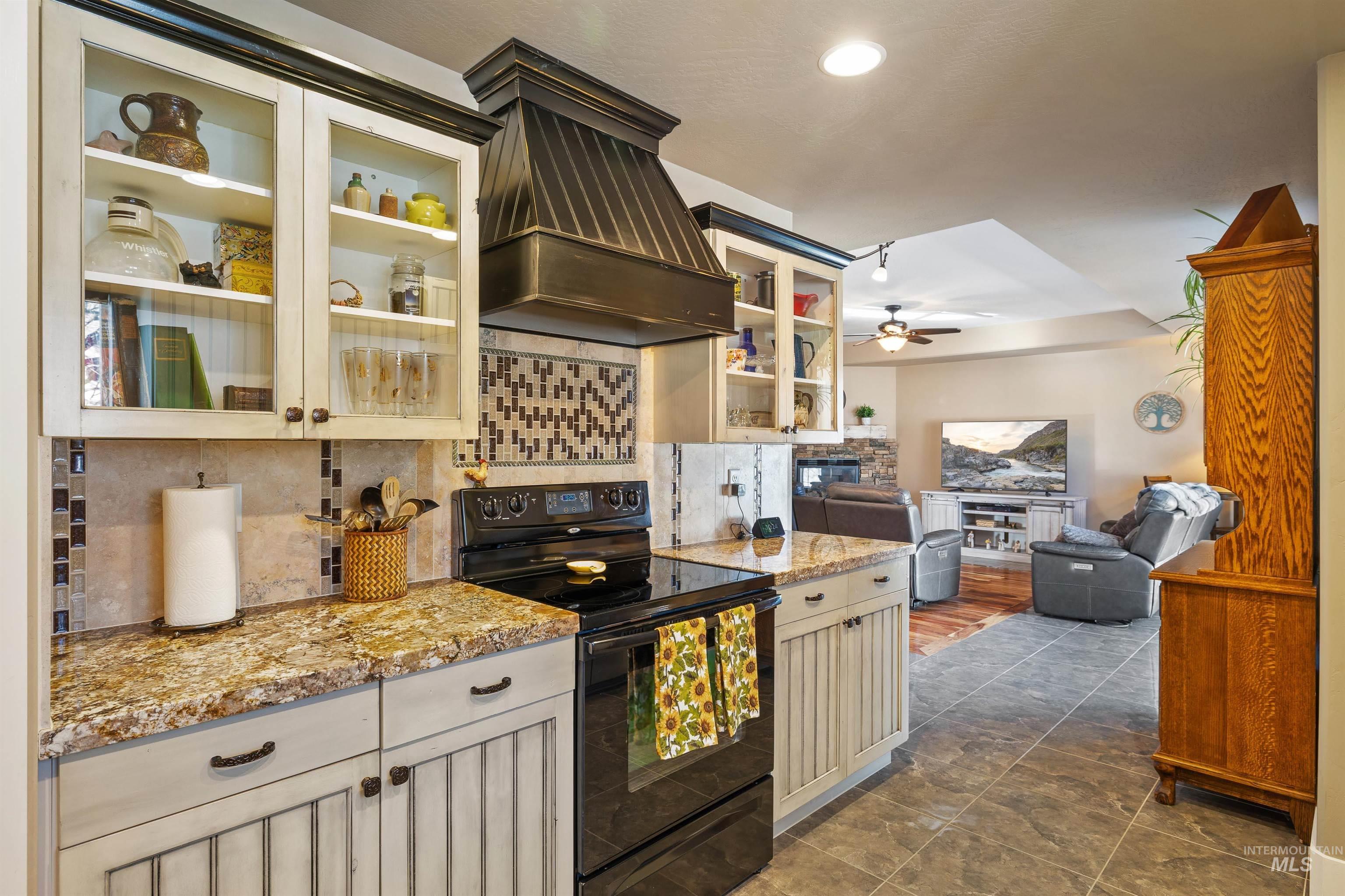 330 Arrowhead Path Twin Falls, ID 83301 - Photo 37 of 37 Kitchen with electric range, decorative backsplash, glass insert cabinets, light stone countertops, and open floor plan