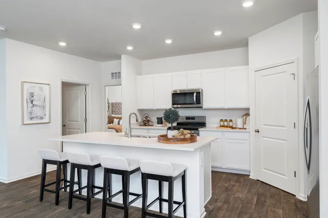 a kitchen with a sink a microwave a refrigerator and white cabinets