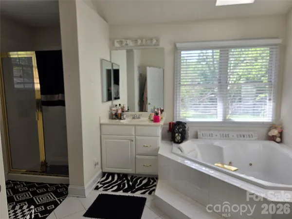 a bathroom with a bathtub a sink a window and a shower