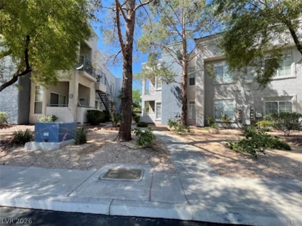 2201 Ramsgate Drive, Unit 915 Henderson, NV 89074 - Photo 1 of 36 A pleasant walkway leads through mature trees to a multi-level building with individual balconies.