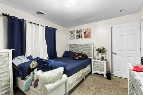 a bedroom with a bed flat screen tv and a large window