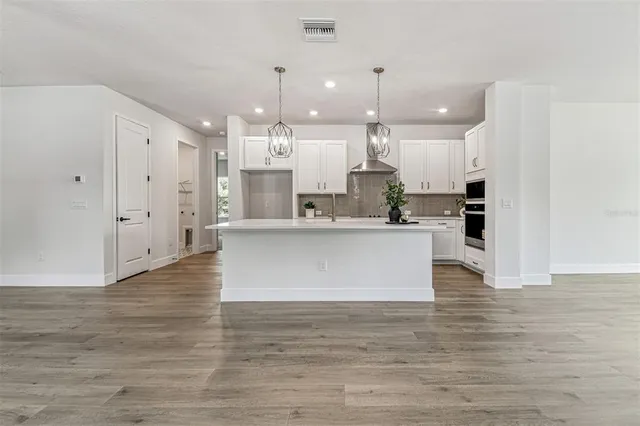 a large kitchen with stainless steel appliances granite countertop a sink a stove and a wooden floors