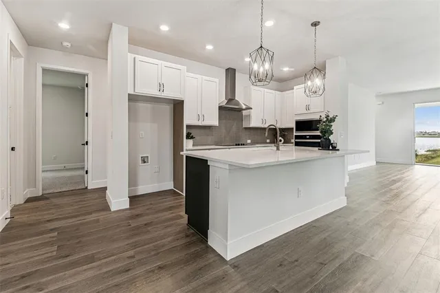 a large kitchen with stainless steel appliances a sink dishwasher a refrigerator and a stove with wooden floor