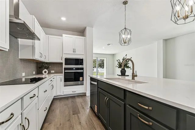 a kitchen with stainless steel appliances granite countertop a stove a sink dishwasher and a refrigerator with wooden floor