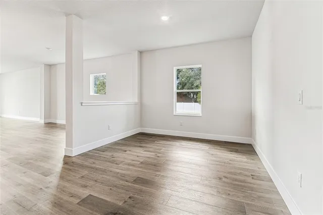 an empty room with wooden floor and window