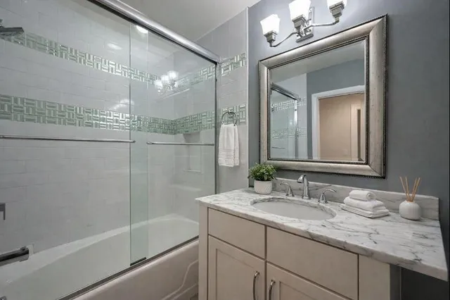 a bathroom with a granite countertop sink a toilet a mirror and shower
