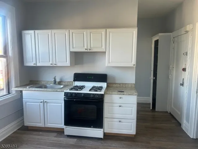a kitchen with a stove white cabinets and a sink