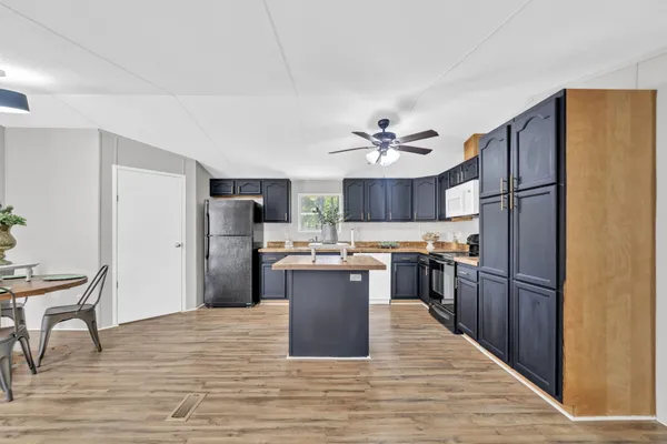 a view of kitchen with stainless steel appliances wooden floor dining table and chairs