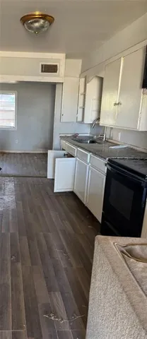 a kitchen with granite countertop a stove a sink and a refrigerator