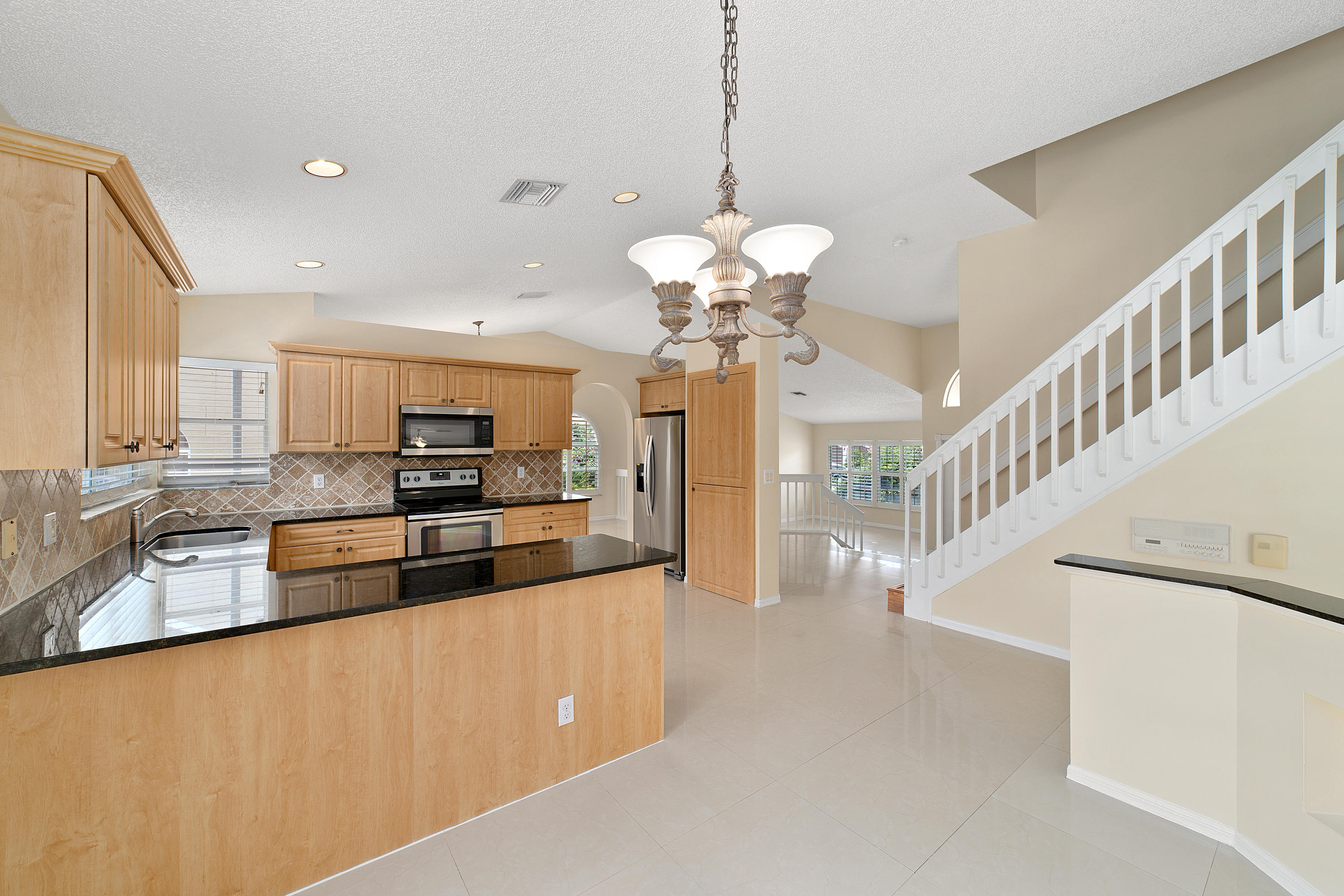 19554 Black Olive Lane Boca Raton, FL 33498 - Photo 12 of 40 a large kitchen with stainless steel appliances a large counter top a stove and a chandelier