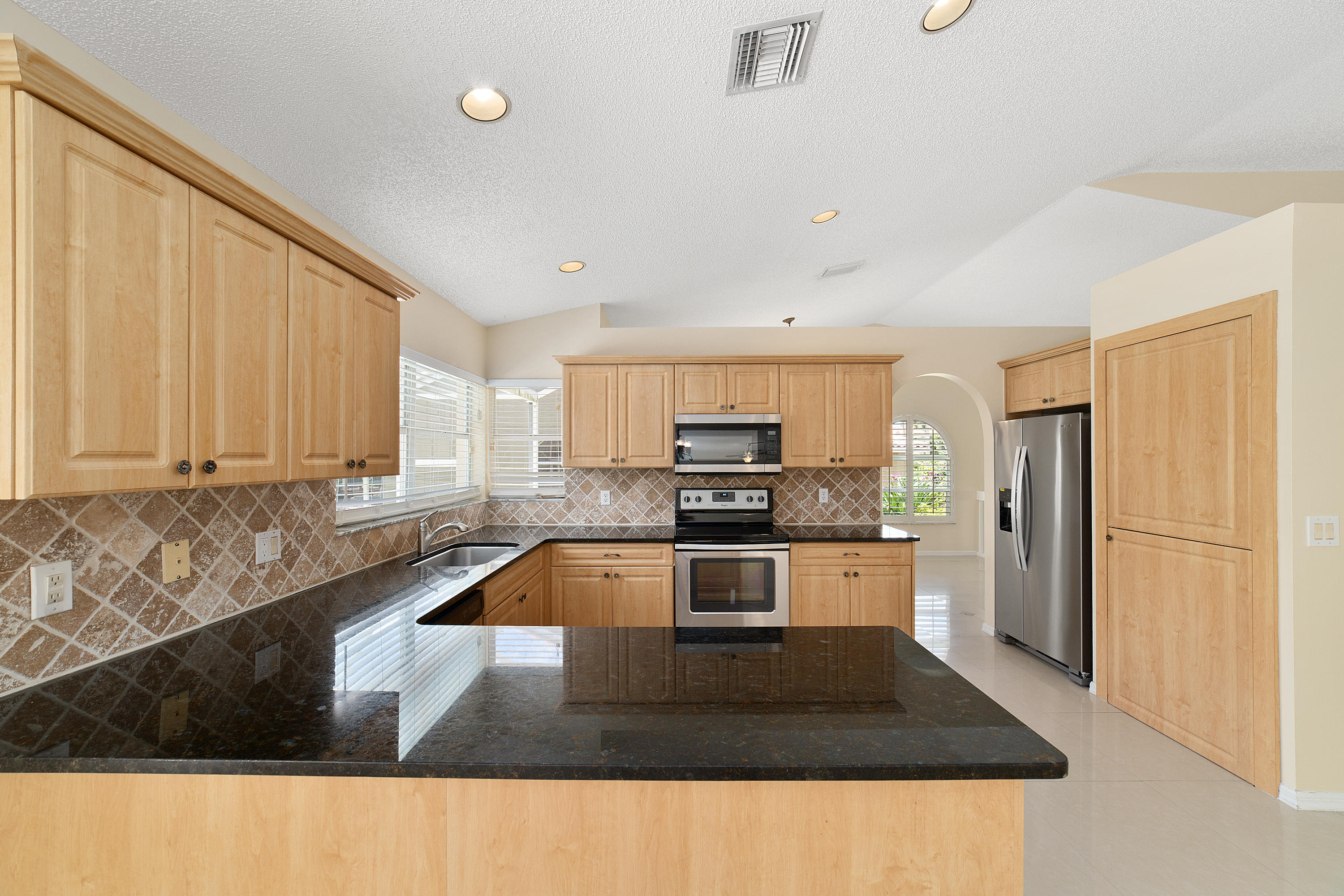 19554 Black Olive Lane Boca Raton, FL 33498 - Photo 14 of 40 a kitchen with stainless steel appliances granite countertop a refrigerator a sink dishwasher a stove with wooden cabinets