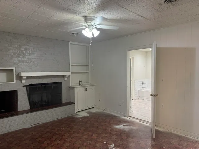an empty room with a fireplace and chandelier fan
