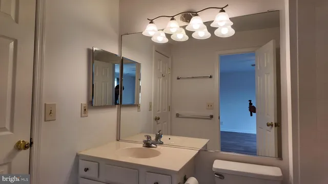 a view of an empty room with wooden floor and a bathroom