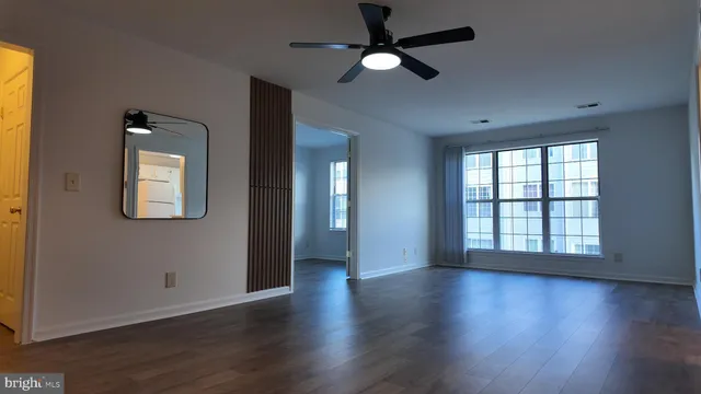 a view of an empty room with wooden floor and a window