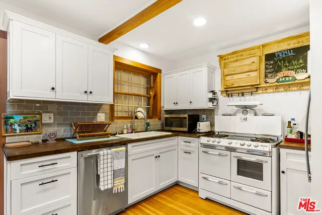a kitchen with stainless steel appliances white cabinets and a stove top oven