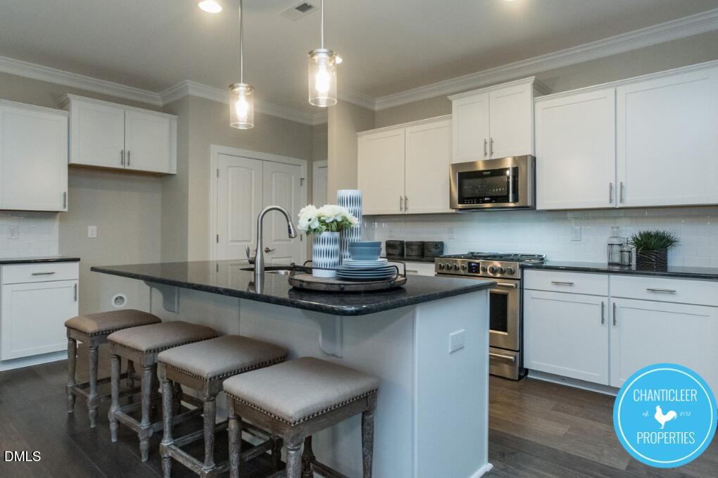 2528 Reynolds Drive Graham, NC 27253 - Photo 7 of 21 a kitchen with stainless steel appliances granite countertop a stove a sink a microwave a refrigerator and white cabinets