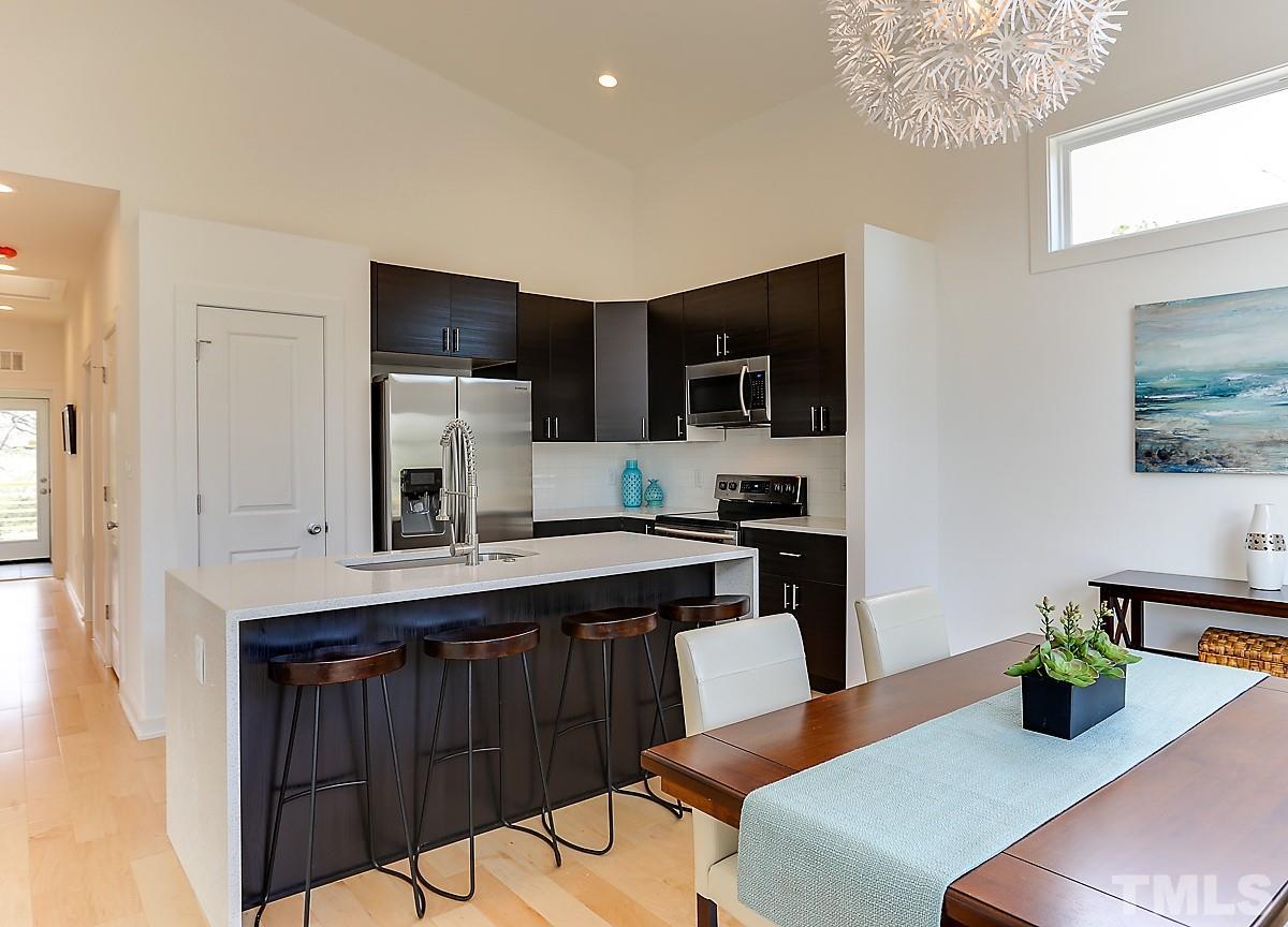 1310 South East Street Raleigh, NC 27601 - Photo 15 of 21 a kitchen with stainless steel appliances granite countertop a sink a stove a microwave a refrigerator a dining table and chairs with wooden floor