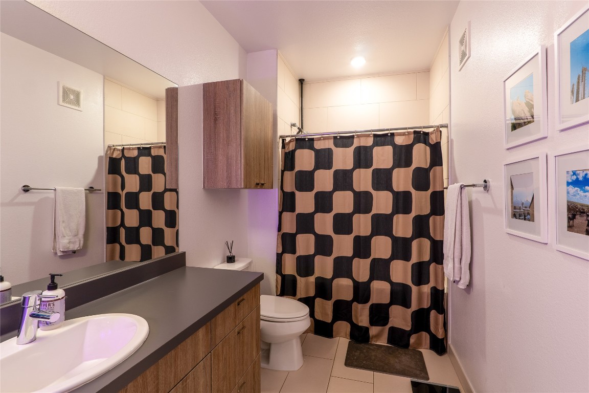 4361 South Congress Avenue, Unit 314 Austin, TX 78745 - Photo 17 of 25 a bathroom with a granite countertop sink a toilet a shower and a mirror